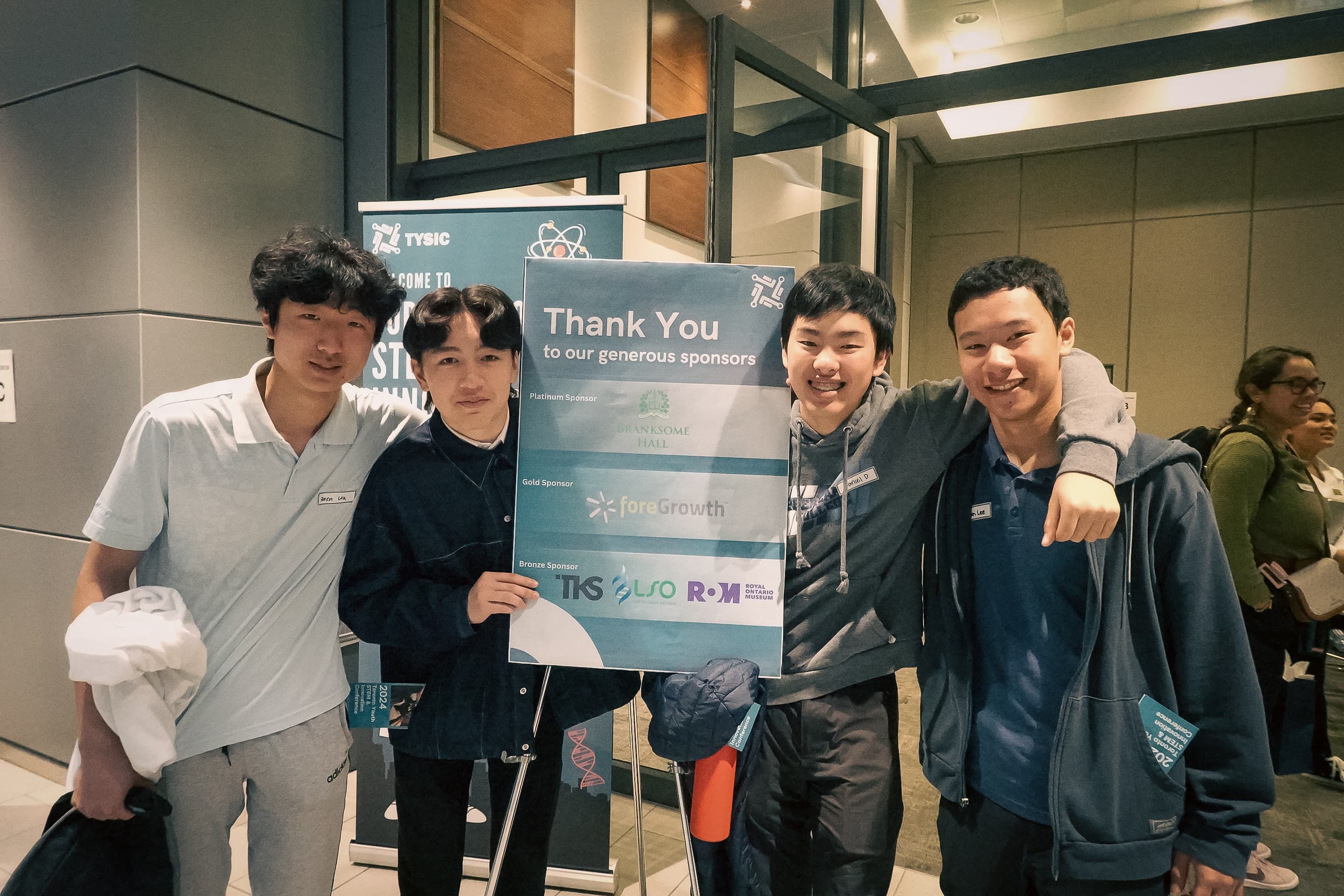 Attendees with a TYSIC sponsor thank-you sign